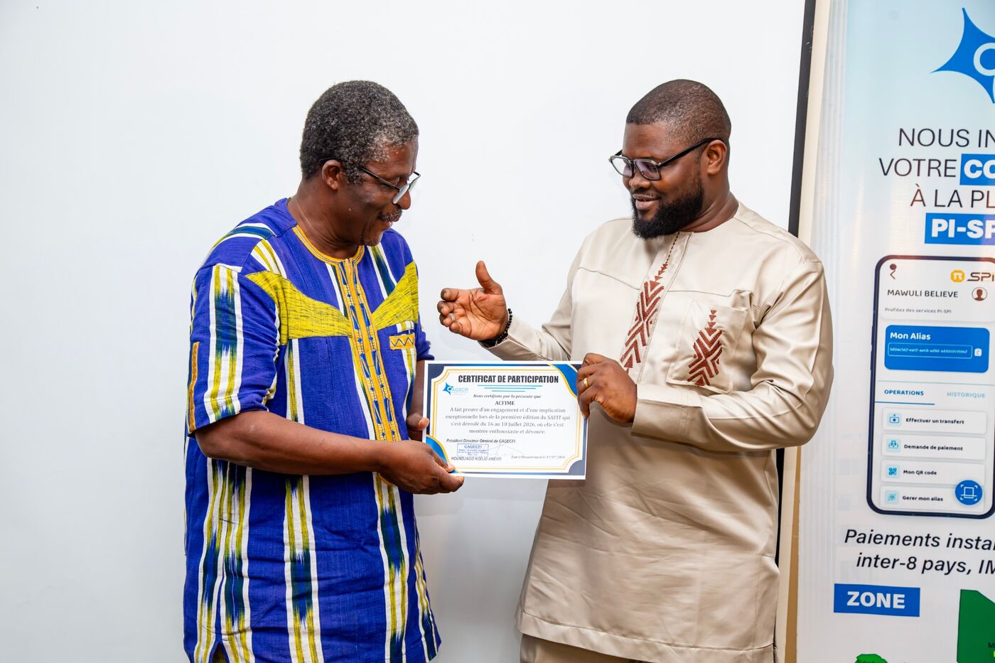 Eklin handing a participation certificate to a man in a colourful tunic, in front of a PI-SPI banner